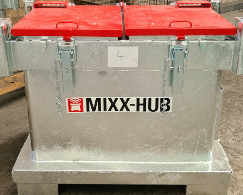 Ein großer Metallcontainer mit zwei roten Deckeln und der Aufschrift MIXX-HUB. Die Deckel werden durch Schnallen verschlossen gehalten.