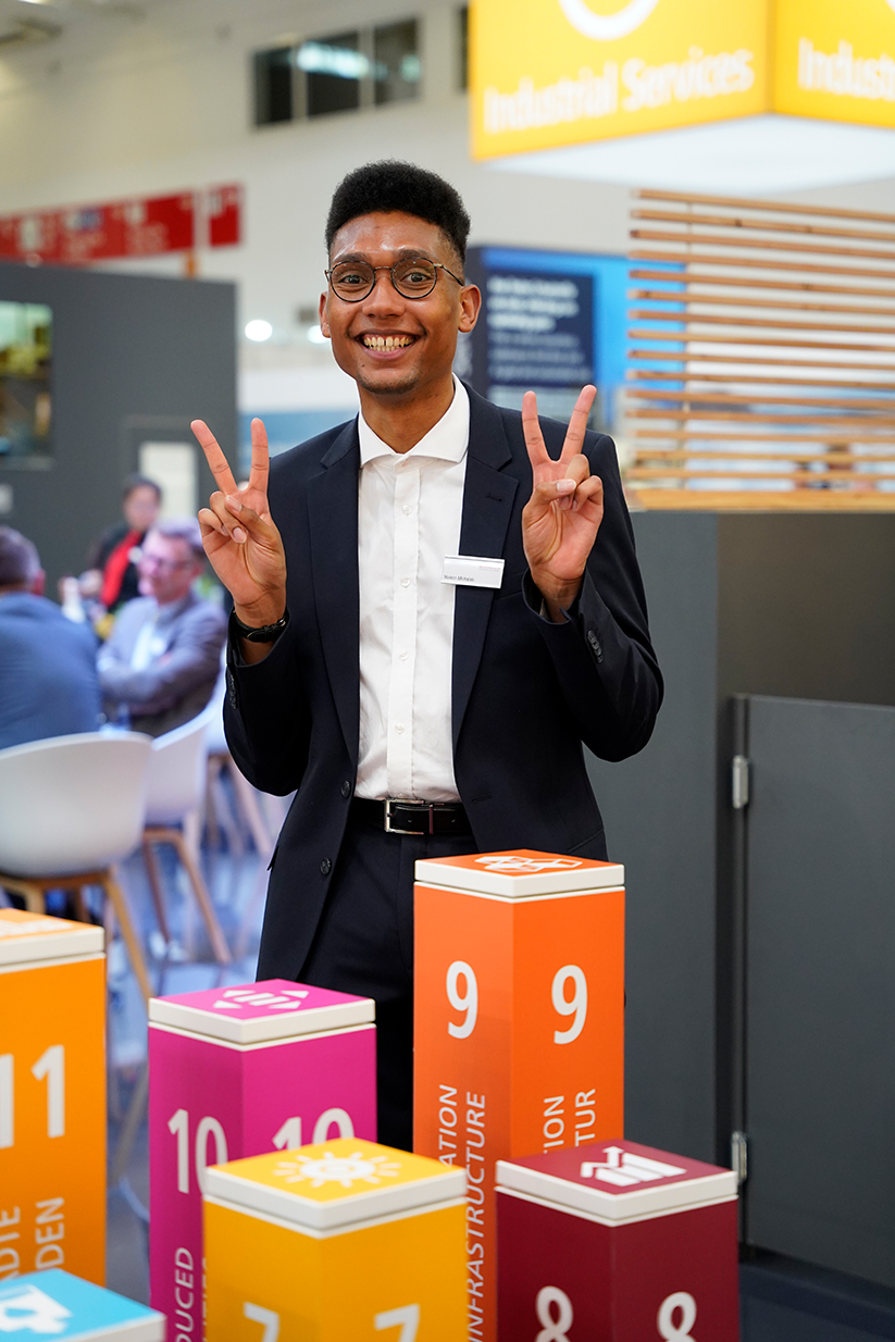 Mitarbeiter auf dem REMONDIS-Stand vor den 17 farbigen Säulen